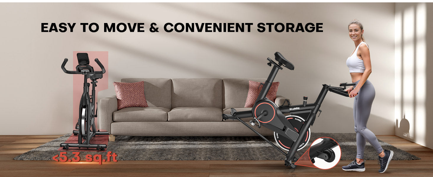 Kuntopyörä, jonka vieressä seisoo nainen, asetettuna puulattialle olohuoneen ympäristössä.